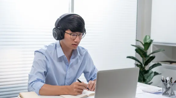 web会議イヤホンマイクをつけてオンライン会議をしている男