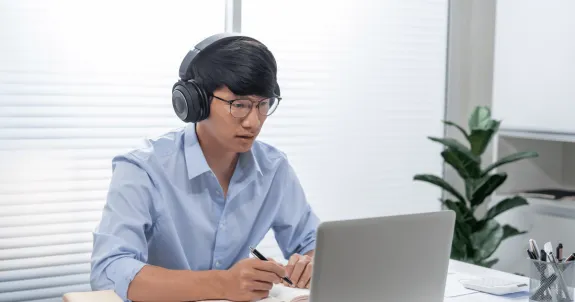 web会議イヤホンマイクをつけてオンライン会議をしている男