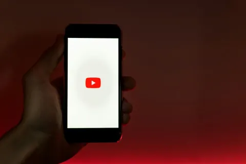 a man hold an iphone which show youtube on the screen