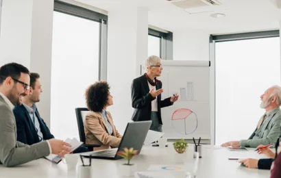 会議室で男性がデジタルボードを使って発表しています。