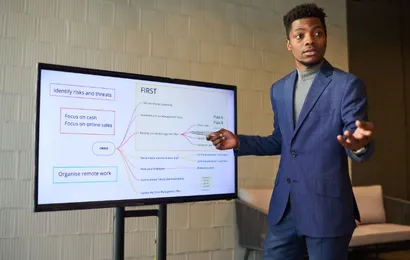 一人の男性が電子ホワイトボードを使って発表しています。