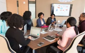 a women presents her ideas to coworkers in a huddle room