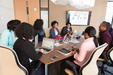 a women presents her ideas to coworkers in a huddle room