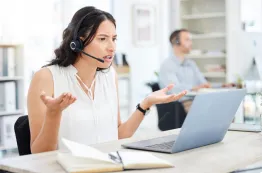A woman wearing a call center headset while working at a customer support desk