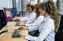 Busy open-plan office where support teams use professional contact center headsets to maintain high call quality amidst background noise.