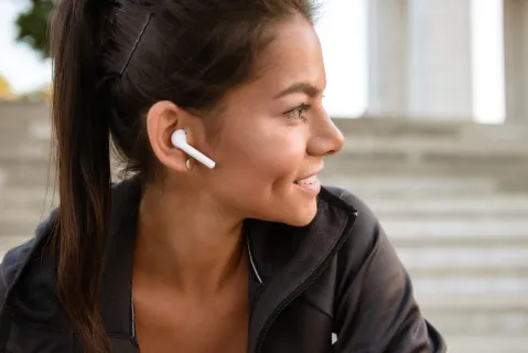 Young woman wearing earbuds, designed for small ears and all-day comfort.
