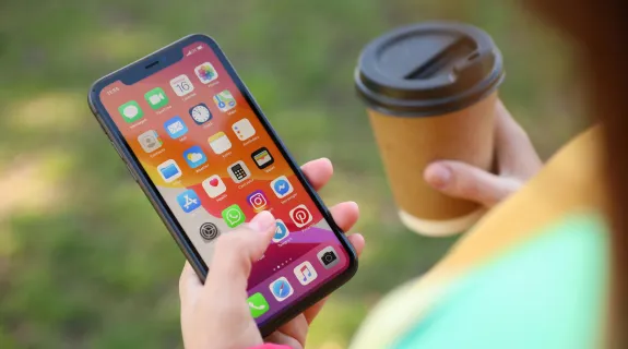 左手にiphone、右手にコーヒーを持った女性