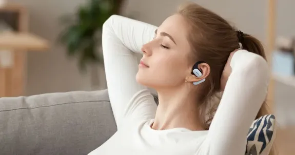 耳にかけるイヤホンをつけて音楽を聴いている女