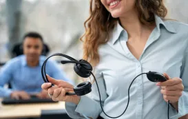 a white woman is holding a lightweight headset with mic​