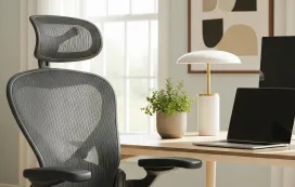 A high-quality black mesh ergonomic office chair with an adjustable headrest and lumbar support in a modern, sunlit home office.