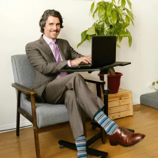 A man sits in desk chairs for back pain