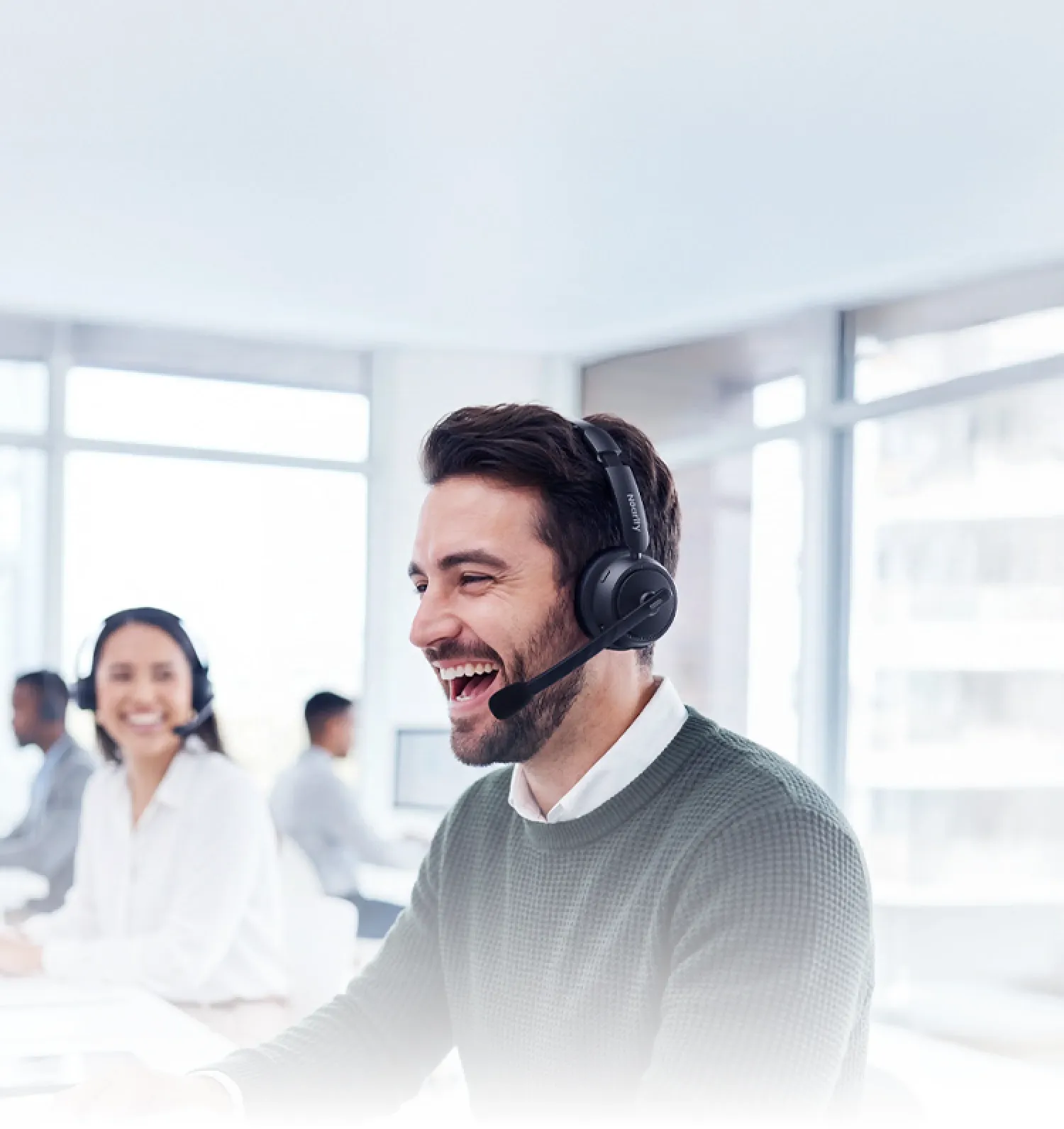 Man in a bright office environment enjoying clear audio with a wireless headset with mic for work, powered by AI noise cancellation.