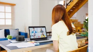 A woman using portable speakerphone in hybrid work.