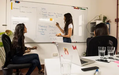 女性一人が壁面ホワイトボードで字を書いています