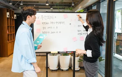 二人がキャスター付きホワイトボードを使っている。