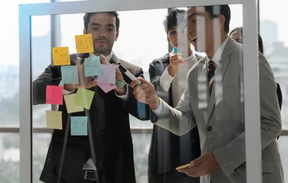 2人がガラスボードの前で会話している